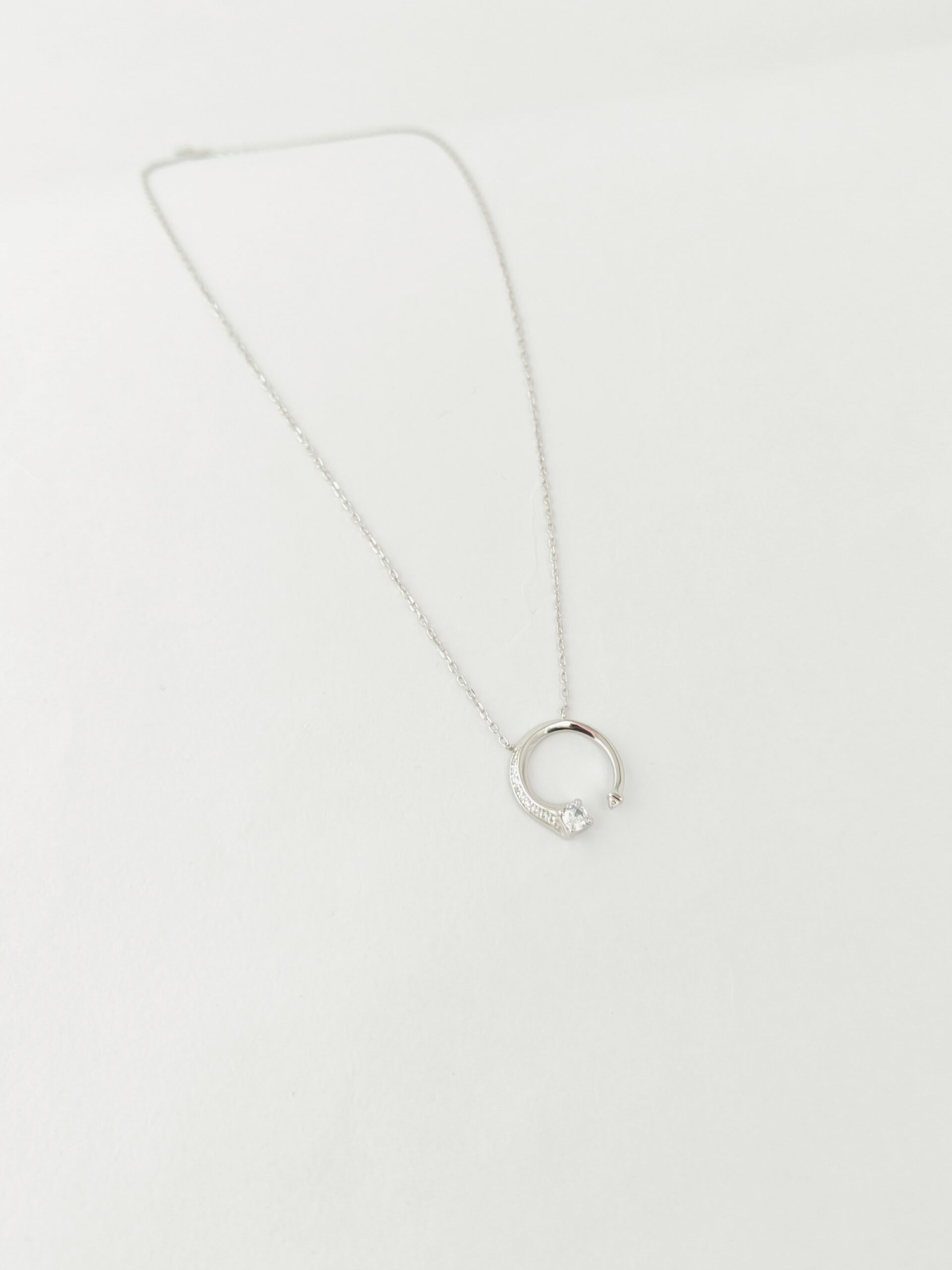 Silver necklace with a circular pendant on a white background